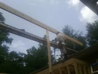 Carpenter setting a ridge beam over a new addition frame — Ice Dam Removal by Roofing Brothers in Lula