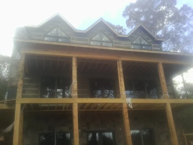Dormers and porch framing on a large log home under construction — Roof Coating work by our crew in Lula