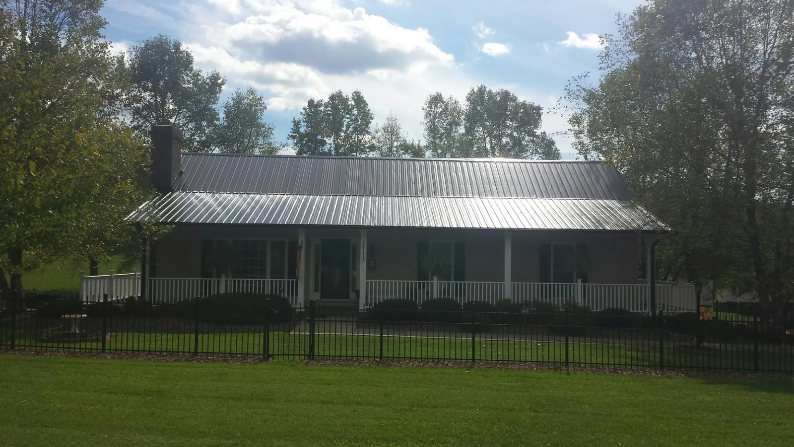 Gray metal roof on a brick ranch with a full width front porch — Gutter Guard Installation work by our crew in Lula