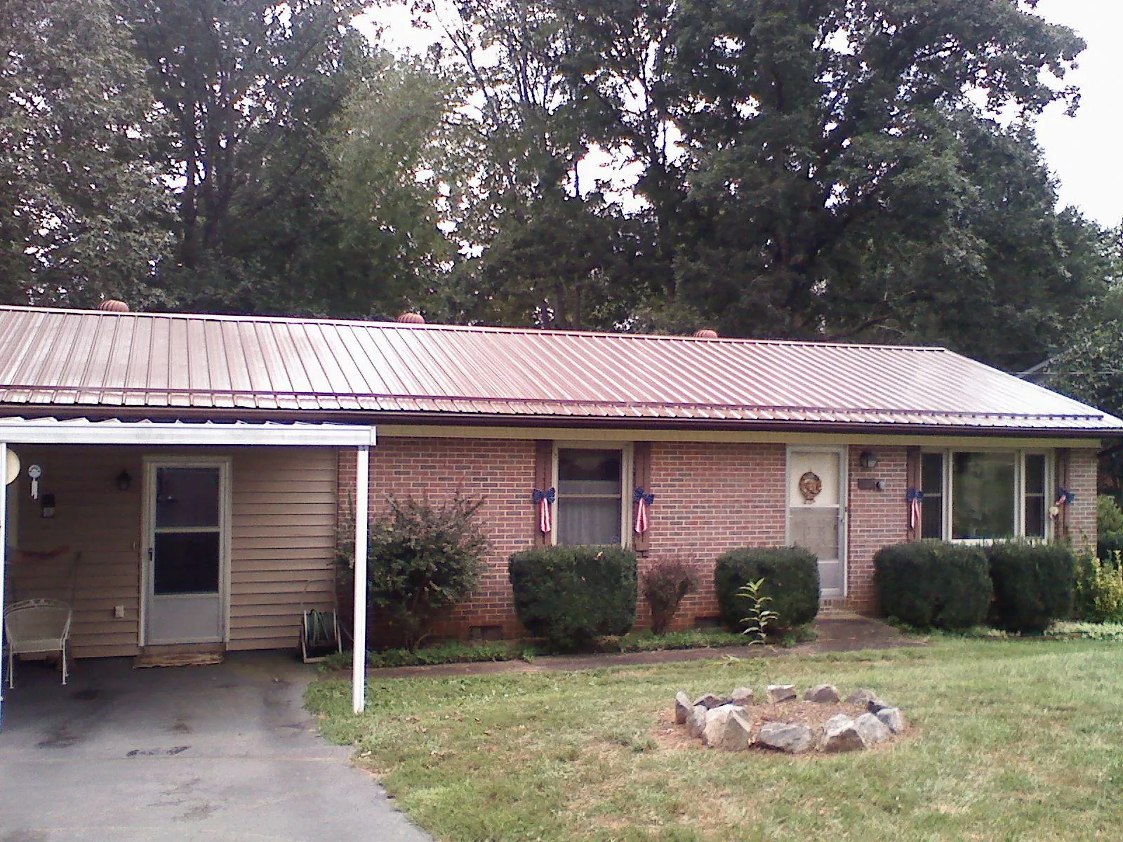 Bronze metal roof and carport on a brick ranch home — Roof Repair work by our crew in Lula