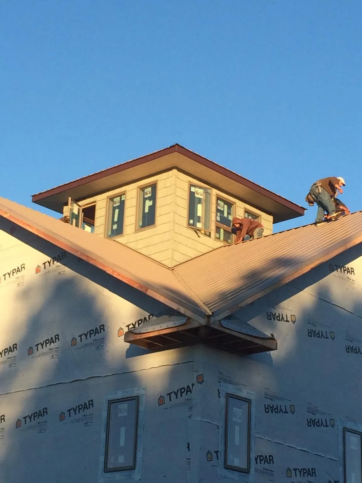 Roofers working around a rooftop cupola on a new metal roof at sunset — Roof Waterproofing in Lula by Roofing Brothers